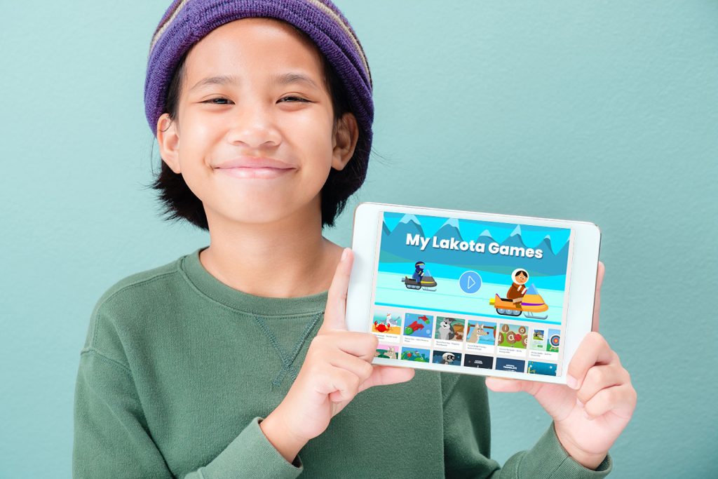 Indigenous child holding ipad that features games in their language.