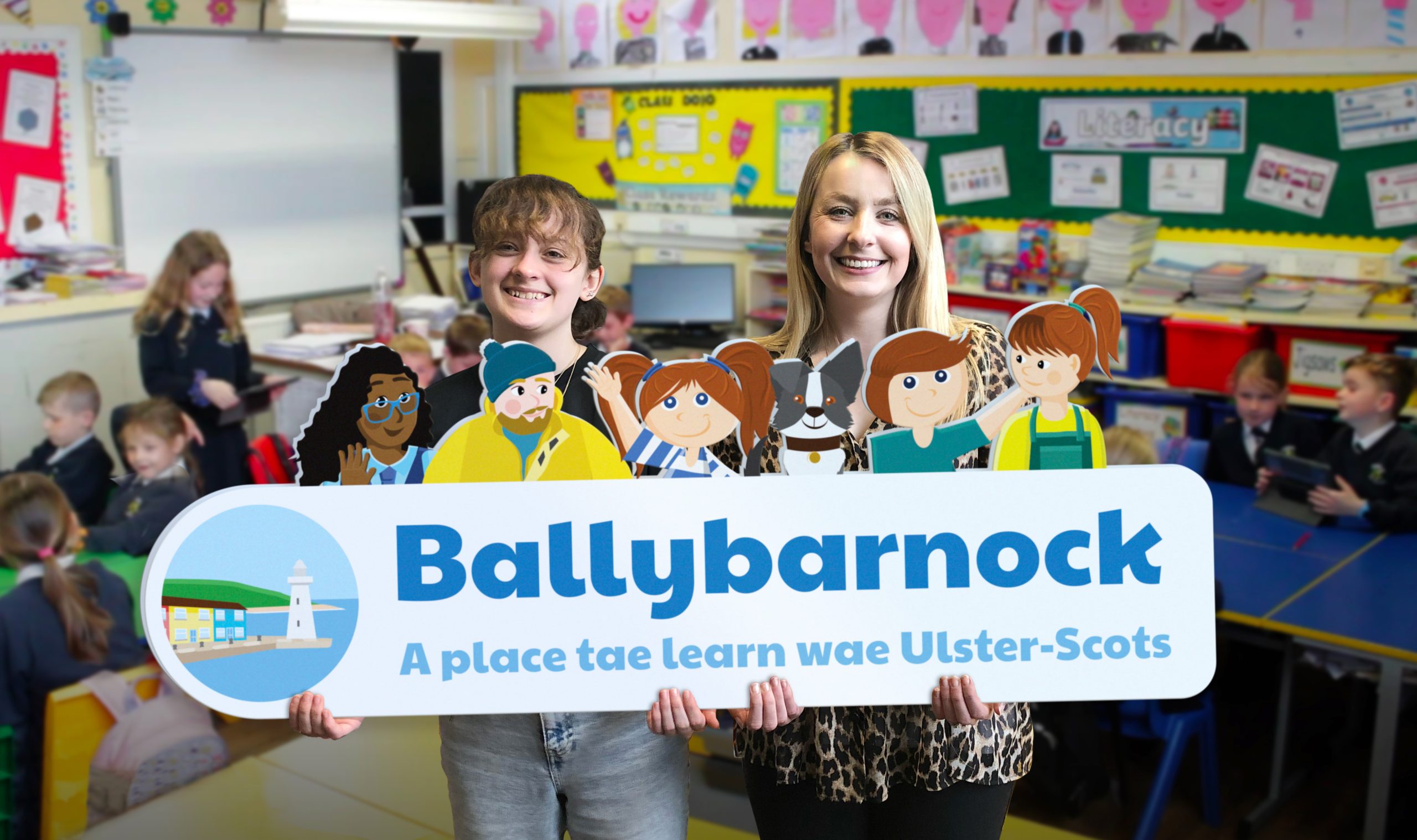 Illustrator and teacher hold up Ballybarnock logo in front of class of children.